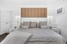 Wood-slat accent paneling, white upholstered headboard, wall-mounted metallic light fixtures, chair rail molding, and wood-finish flooring