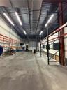 Industrial warehouse space featuring high ceilings, exposed structural steel, heavy-duty industrial racking, concrete flooring, and linear overhead li