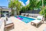 Private backyard featuring an in-ground swimming pool, stone-finish decking, mature palm trees, and perimeter privacy fencing