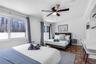 Bedroom featuring tile flooring, built-in shelving, a ceiling fan, and large windows with sliding door access to exterior space