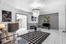 Living space featuring large-format tile flooring, two-tone wall paint, waist-high chair rail molding, and a tiered chandelier fixture