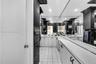 Dual-sink vanity with white cabinetry and solid surface countertops, expansive wall-to-wall mirror, and contrasting black tile backsplash and wall acc