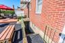 Red brick exterior featuring a wood deck, paved ground surface, and metal stair railing