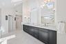 Dual-vanity bathroom featuring dark cabinetry, expansive stone countertops, integrated floor-to-ceiling storage, skylights, and polished metal fixture