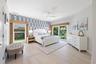 Room featuring wood-finish flooring, accent wallpaper, a ceiling fan, and sliding glass doors providing outdoor access