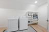 Dedicated laundry space featuring wood-finish flooring, recessed lighting, and wall-mounted white built-in shelving