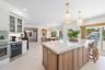 Kitchen featuring a large central island with light-toned stone surfacing, white cabinetry, built-in dual oven, under-counter wine refrigerator, and h