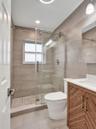 Bathroom featuring a walk-in shower with sliding glass door, linear tile surround, and pebble-style floor