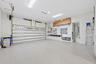 Spacious garage featuring an epoxy-coated floor, integrated wall-mounted slat board storage system, overhead fluorescent lighting, and a multi-panel s