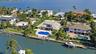 Waterfront property featuring a private boat dock, swimming pool, paved patio, and multi-level roofline