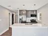 Kitchen featuring gray cabinetry, stainless steel appliances, white quartz countertops, mosaic tile backsplash, and dual pendant lighting