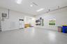 Garage interior featuring speckled epoxy flooring, built-in cabinetry, a wall-mounted ductless heating and cooling unit, overhead lighting, and a wind