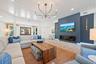 Tongue-and-groove vaulted ceiling, linear fireplace with a matte blue surround, custom metal-spoke chandelier, and recessed lighting