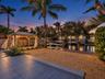 Waterfront property featuring a covered timber-framed gazebo, wooden dock, gravel landscaping, and large-format tile patio