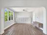 Architectural archway, wood-finish flooring, full-wall built-in cabinetry, wall-mounted floating console, and ceiling fan with integrated lighting