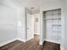 Bedroom 3. Wood-finish flooring featuring a built-in closet with adjustable wire shelving and a wall-mounted pegboard organizer