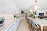 Kitchen featuring white shaker-style cabinetry, a large center island with stone-finish countertops, custom range hood, built-in stainless steel appli