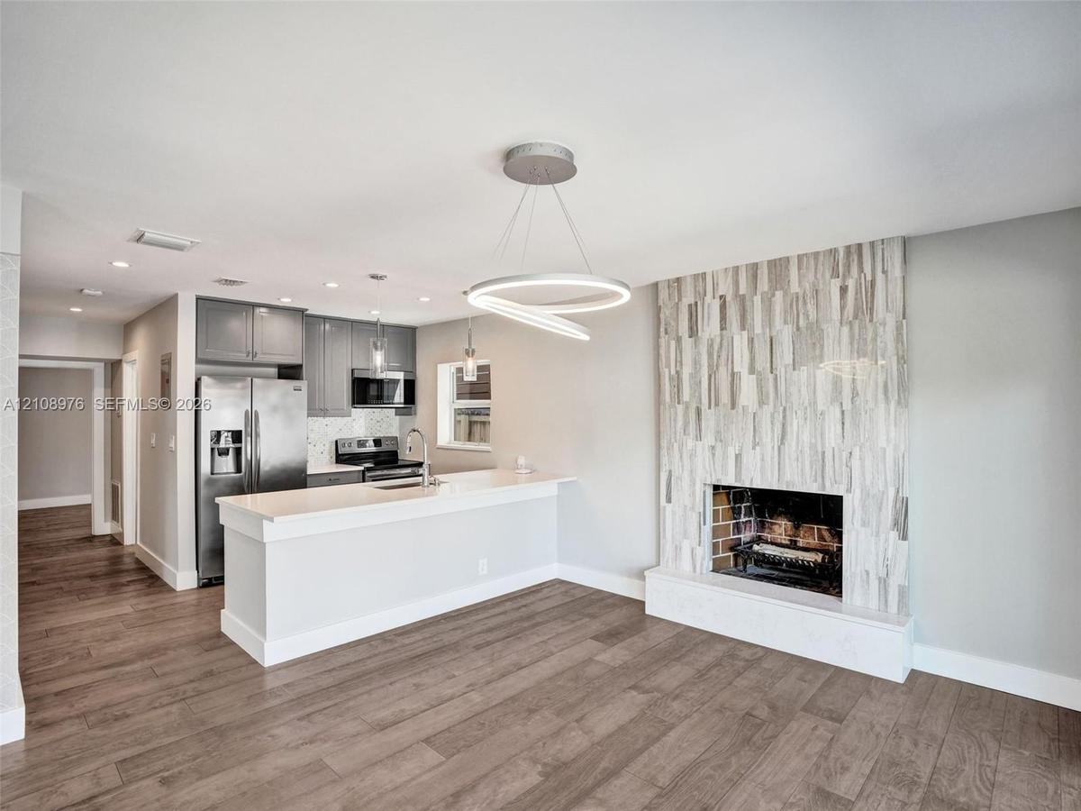 Open concept interior featuring wood-finish flooring, a kitchen with quartz countertops and stainless steel appliances, and a floor-to-ceiling texture