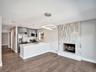 Open concept interior featuring wood-finish flooring, a kitchen with quartz countertops and stainless steel appliances, and a floor-to-ceiling texture
