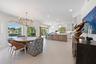 Open-concept kitchen and dining area featuring large-format tile flooring, a multi-tone kitchen island, white shaker-style cabinetry, and a circular m