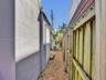 Side exterior area featuring a concrete pathway, gravel ground cover, and wood privacy fencing