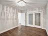 Wood-finish flooring featuring a square, multi-faceted crystal ceiling fixture, dual-panel sliding doors with frosted glass inserts, and a six-panel i
