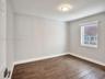 Bedroom 2. Interior space featuring neutral wall paint, wood-finish flooring, a flush-mount ceiling light fixture, and a single-hung window with a rol