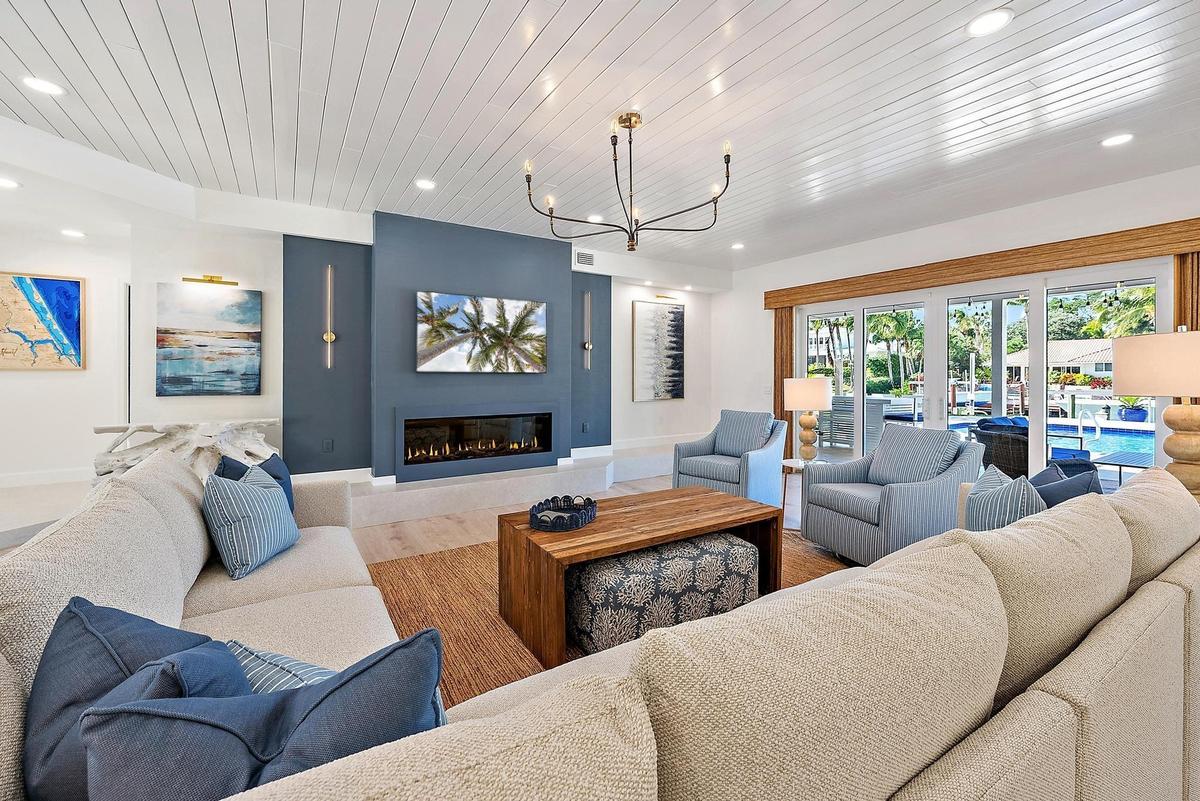 Spacious room featuring a white tongue-and-groove plank ceiling, recessed lighting, a modern linear fireplace with a blue accent wall, a minimalist bl