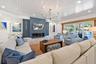 Spacious room featuring a white tongue-and-groove plank ceiling, recessed lighting, a modern linear fireplace with a blue accent wall, a minimalist bl