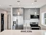 Kitchen featuring grey shaker-style cabinetry, stainless steel appliances, white stone-finish countertops, a mosaic tile backsplash, and dual glass pe