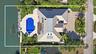 Waterfront property featuring a private dock, expansive paved patio, inground pool, and metal roofing