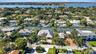 Aerial perspective of a waterfront community featuring deep-water canal access, private boat docks, paved driveways, manicured tropical landscaping, a