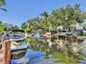 Waterfront property featuring a private boat lift, concrete bulkhead, mature trees, and direct canal access