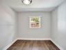 Bedroom 3. Neutral wall paint, wood-finish flooring, and single-pane window with installed window treatment, complemented by a flush-mount ceiling fix