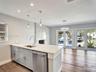 Kitchen island featuring light-toned cabinetry, a stone-finish countertop, stainless steel undermount sink, and recessed lighting