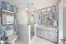 Bathroom featuring a glass-enclosed shower with stone-tile surround, custom wood-finish cabinetry, stone-top vanity, and dual wall-mounted mirrors wit