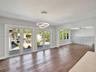 Living space featuring wood-finish flooring, dual sets of French doors, an integrated circular LED light fixture, and custom built-in cabinetry with a
