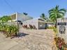 Single-story residence featuring a paved brick driveway, low-slope roofline, light-toned exterior finish, and fenced perimeter