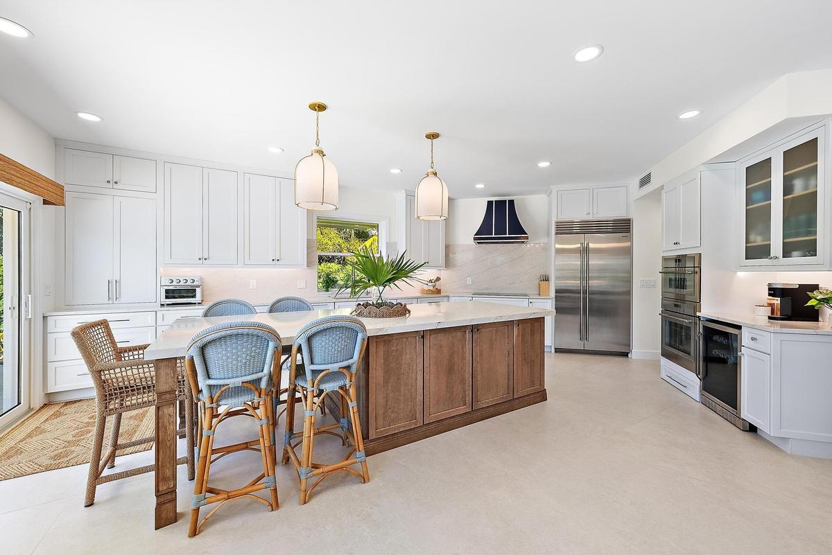 Kitchen featuring white cabinetry, a wood-finish central island with a stone countertop, stainless steel double-door refrigerator, built-in double ove