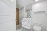 Modern floating vanity with a white vessel sink and stone-finish countertop, walk-in shower with a glass enclosure, floor-to-ceiling mirror, and neutr