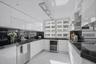 Kitchen featuring high-gloss white cabinetry, dark stone countertops, stainless steel appliances, a built-in wine cooler, and a linear pendant light f