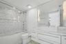 Bathroom featuring a white vanity with a stone-finish countertop and square vessel sink, full-width wall mirror with integrated lighting, glass-enclos