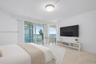 Floor-to-ceiling glass sliders, stone tile flooring, circular flush-mount ceiling light, and coastal ocean horizon