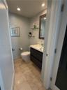 Modern powder room featuring a wall-mounted floating vanity, textured tile accent wall, recessed ceiling lighting, and tile flooring
