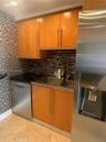 Kitchen area featuring flat-panel wood cabinetry, a stainless steel double-basin sink with a gooseneck faucet, a stainless steel dishwasher, a full-si