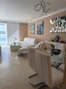 Polished stone flooring, floor-to-ceiling sliding glass doors, horizontal slat blinds, and decorative multi-arm ceiling lighting