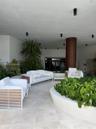 Covered outdoor lounge area featuring large-format stone tile flooring, recessed ceiling lighting, a prominent architectural column with wood-finish c