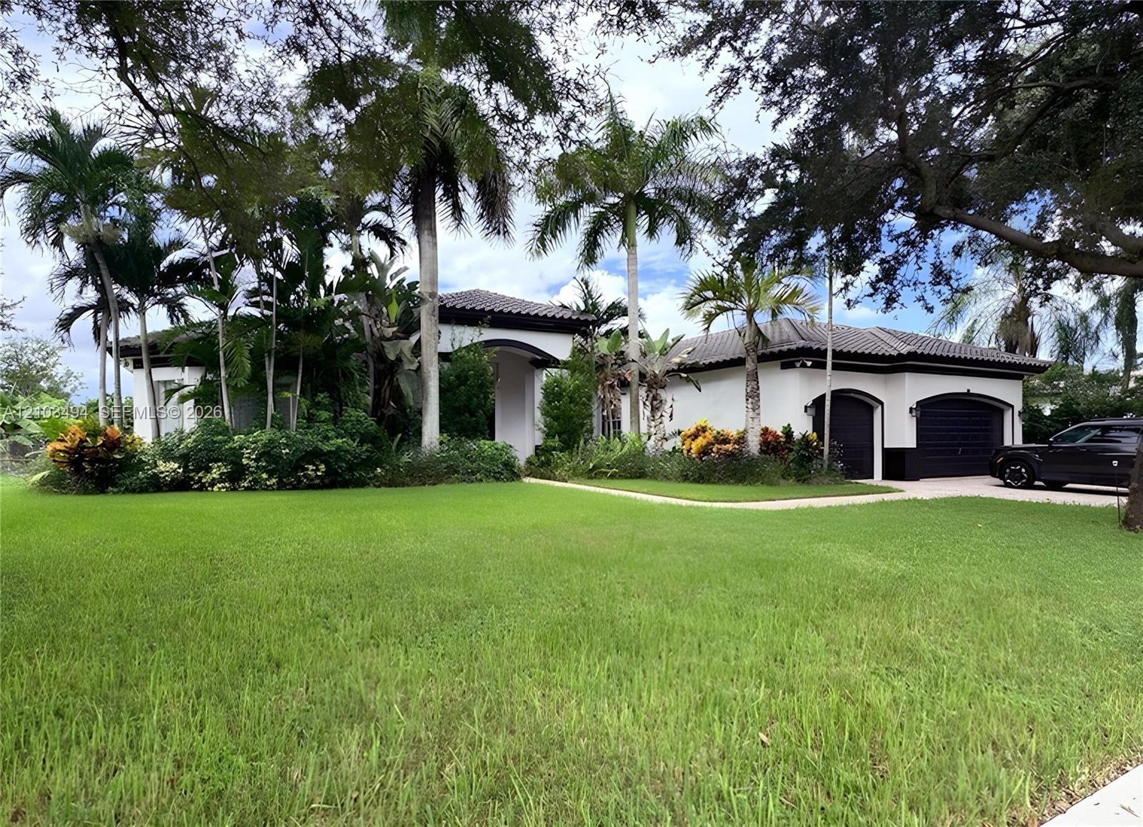 Single-story residence featuring a tile roof, stucco exterior, two-car garage, and mature palm landscaping