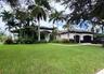 Single-story residence featuring a tile roof, stucco exterior, two-car garage, and mature palm landscaping