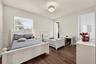 Bedroom featuring wood-finish flooring, a neutral color palette, natural light via horizontal blinds, and a circular drum flush-mount light fixture